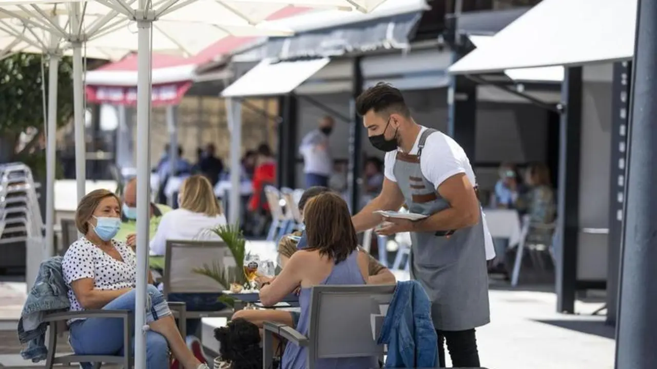 <p> Varias personas en una terraza del paseo mar&iacute;timo de la playa de Sanxenxo </p>