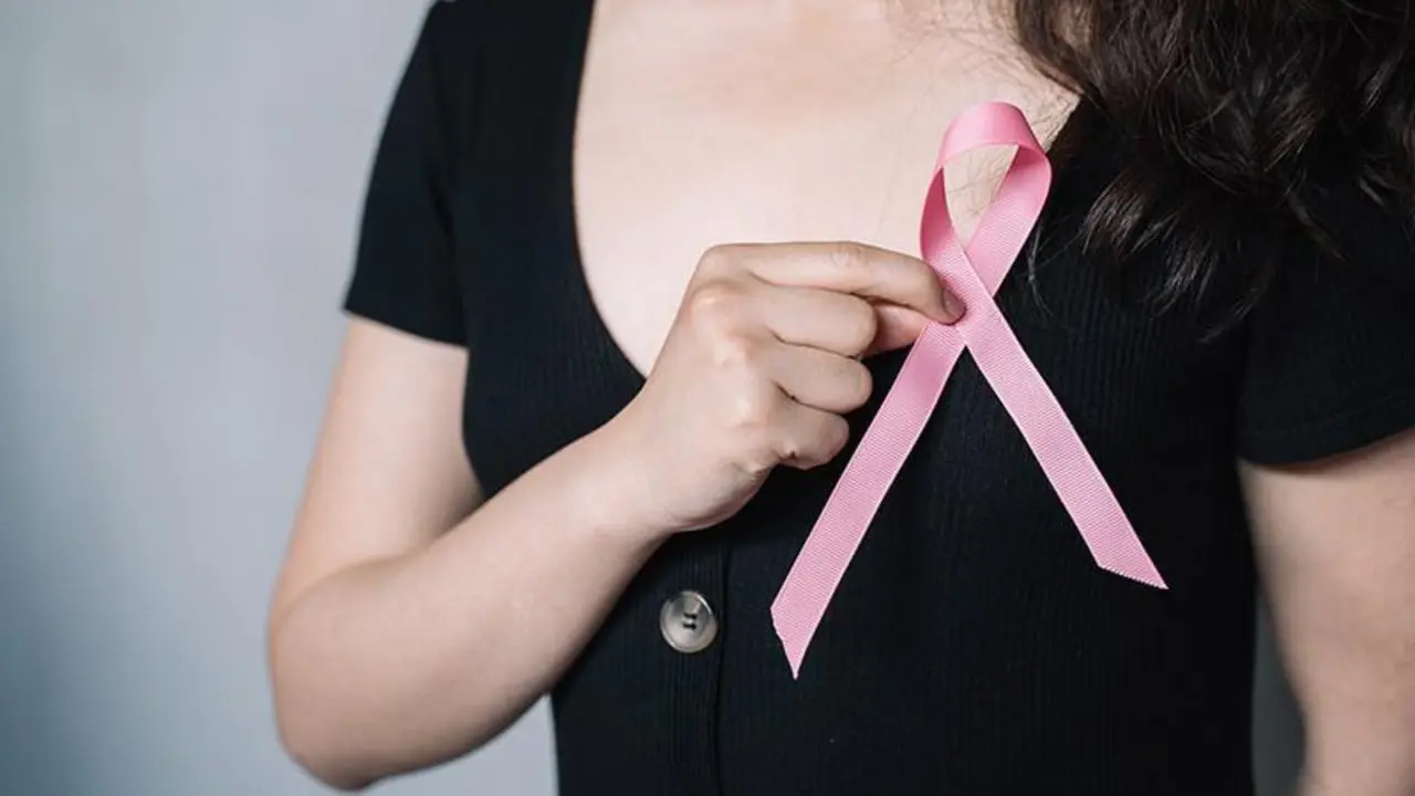 <p> Una mujer se coloca el lazo rosa en solidaridad con las afectadas por c&aacute;ncer de mama. </p>