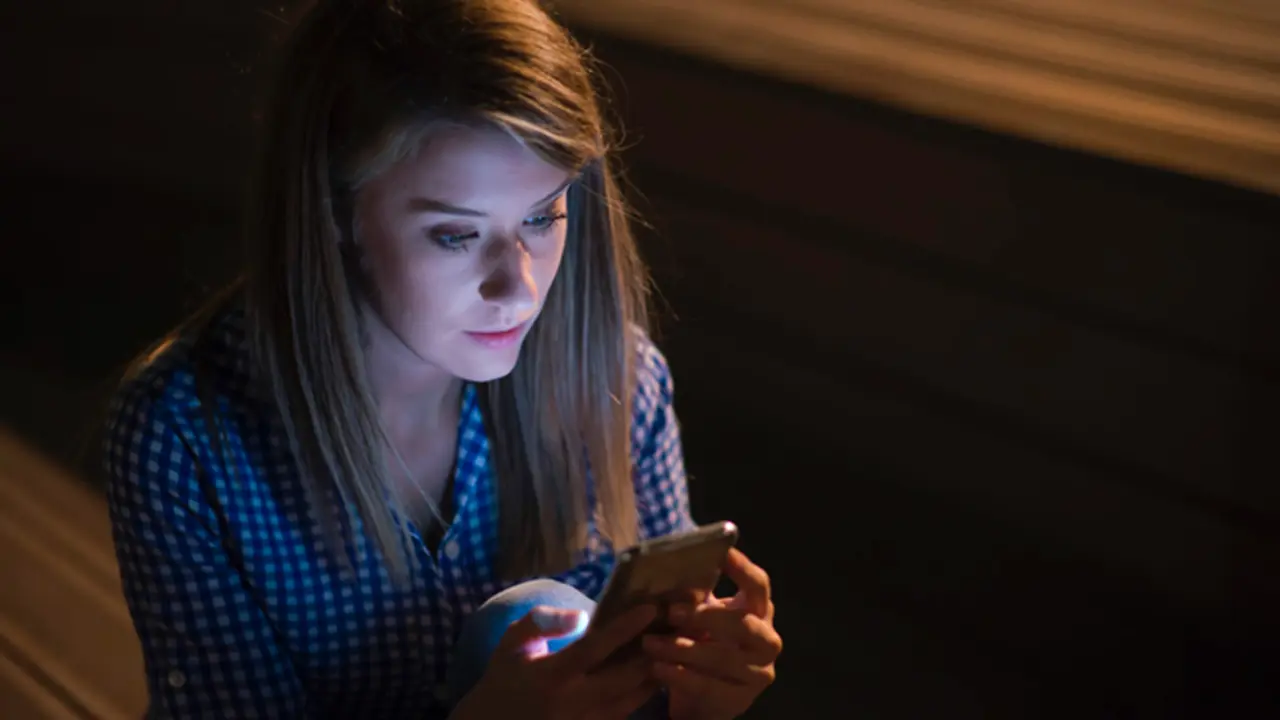 <p> Una joven lee mensajes en su tel&eacute;fono m&oacute;vil. </p>