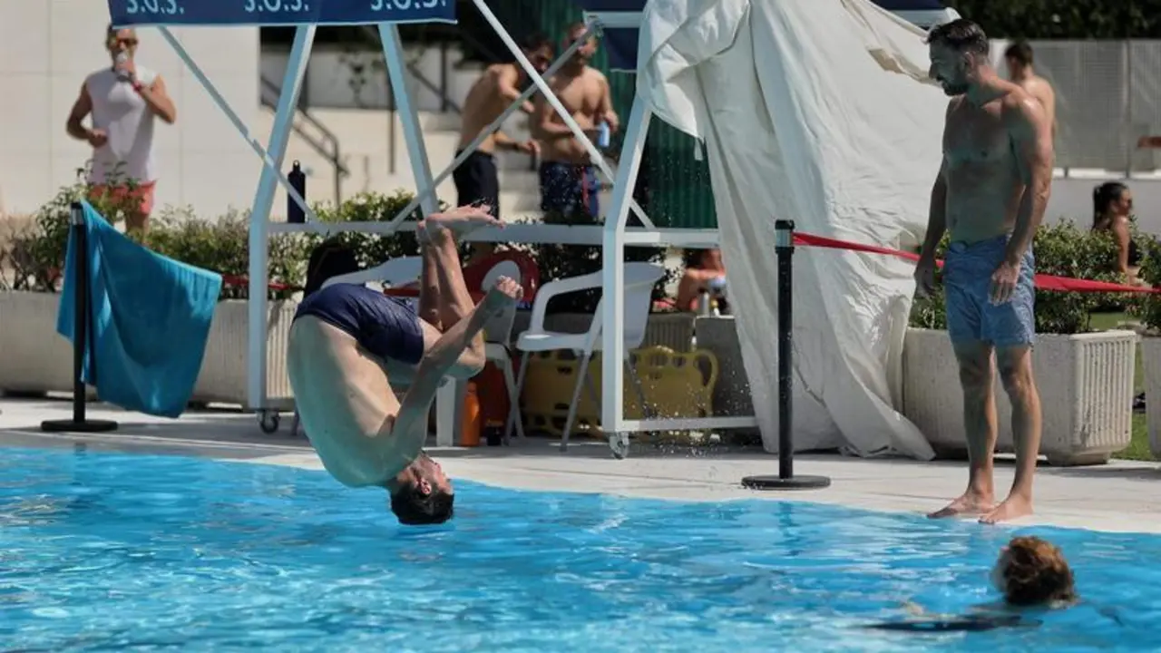 <p> Un hombre salta de voltereta a una piscina en la Casa de Campo, Madrid </p>