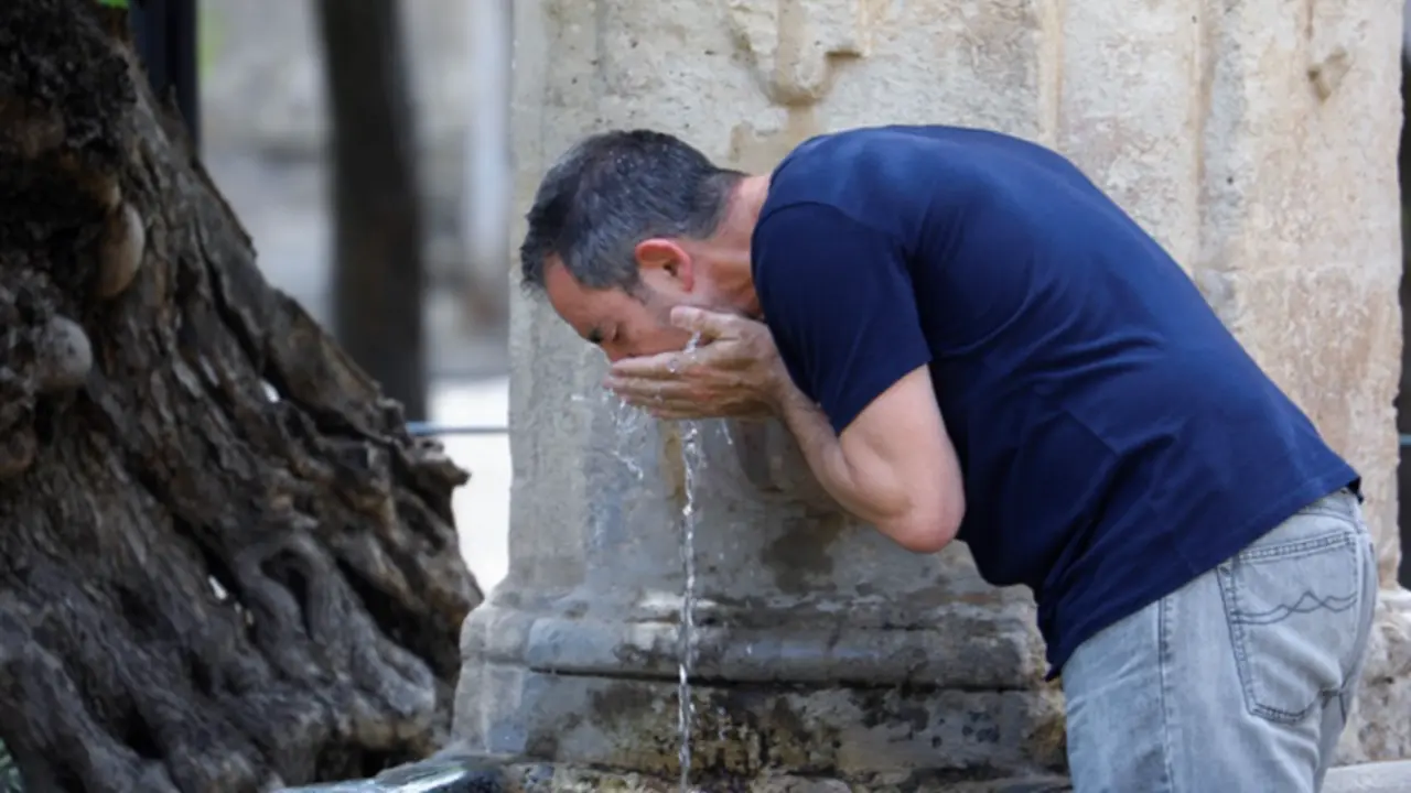 <p> Un hombre bebe agua de una fuente en C&oacute;rdoba </p>