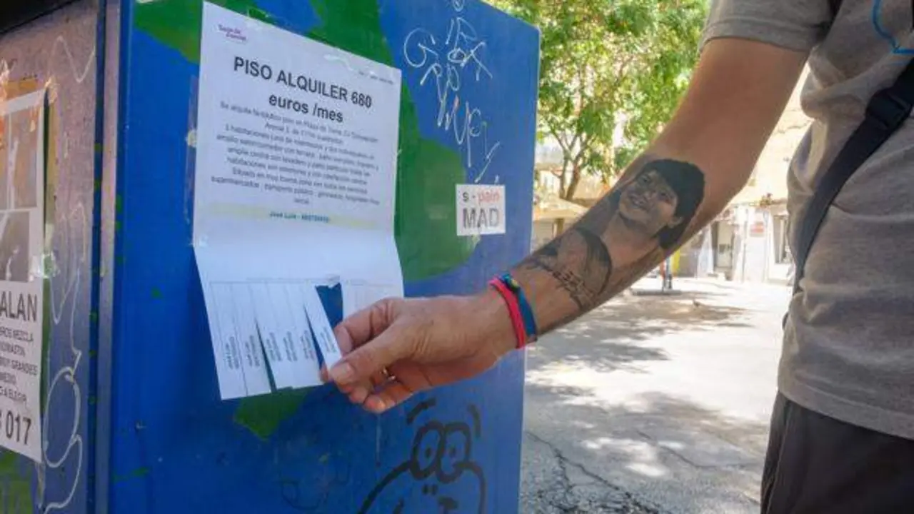 <p> Estudiante cogiendo el numero de contacto de un piso de alquiler </p>