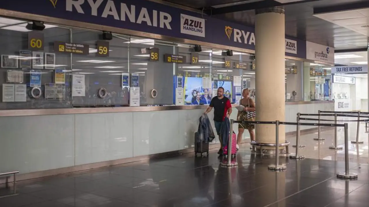 <p> Dos personas pasan junto a una ventanilla de Ryanair en el Aeropuerto Josep Tarradellas Barcelona </p>