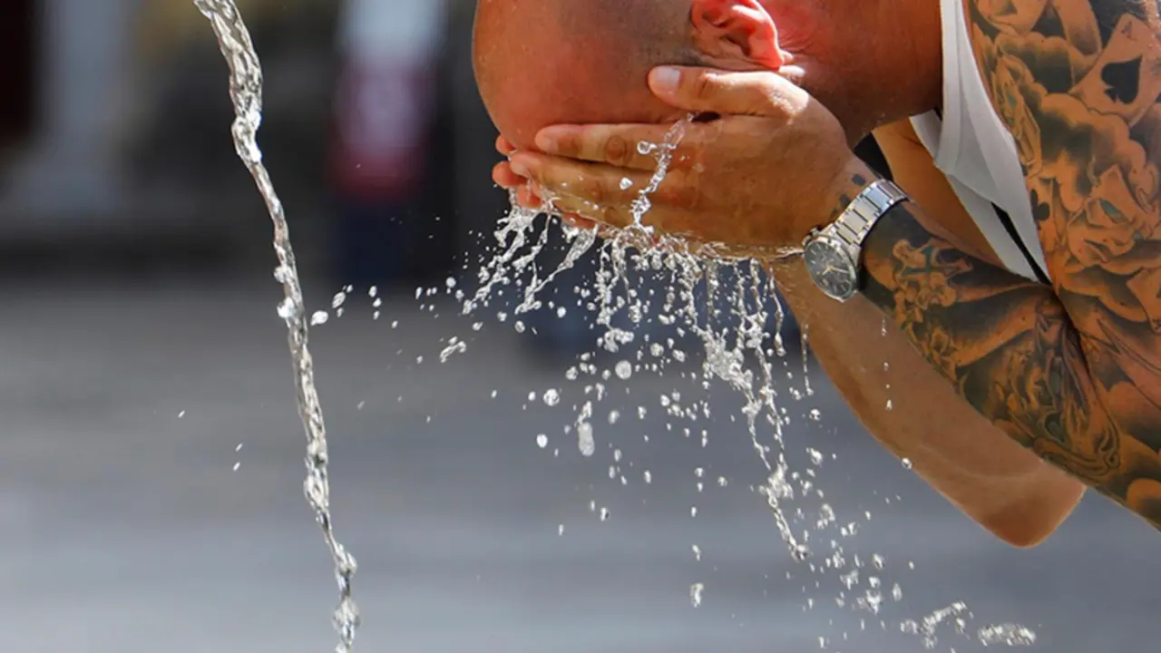 <p> Un hombre se refresca ante la ola de calor </p>