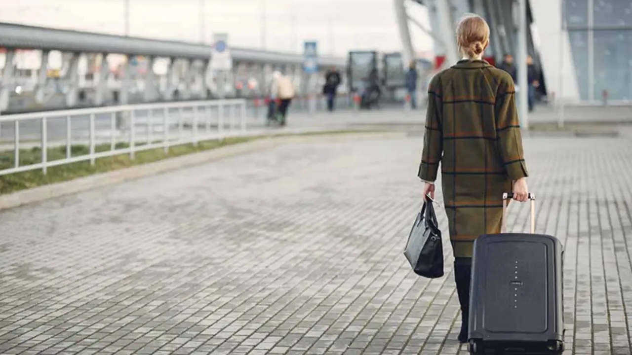  Una mujer camina con su maleta camino del aeropuerto. 