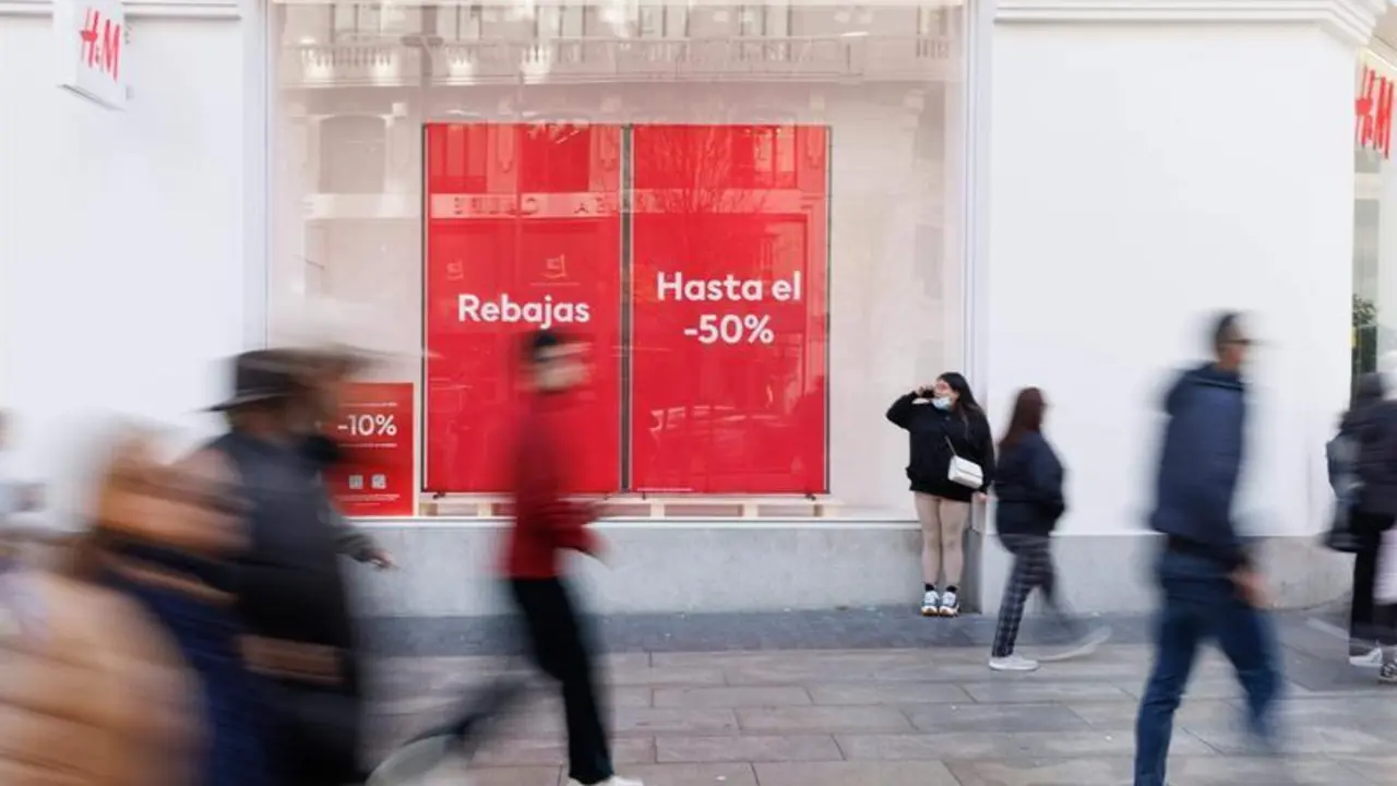  Varias personas caminan frente a una tienda de H&M con el cartel de rebajas 