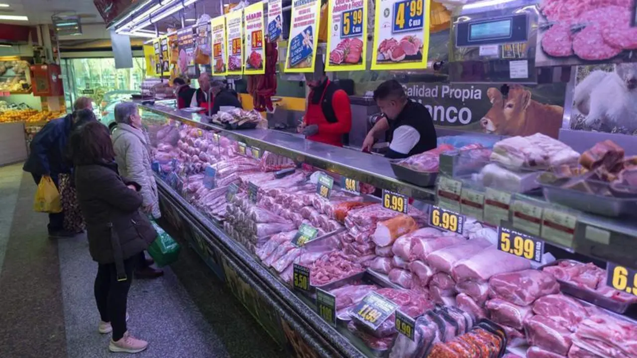  Varias personas compran en una carnicer&iacute;a en un mercado 