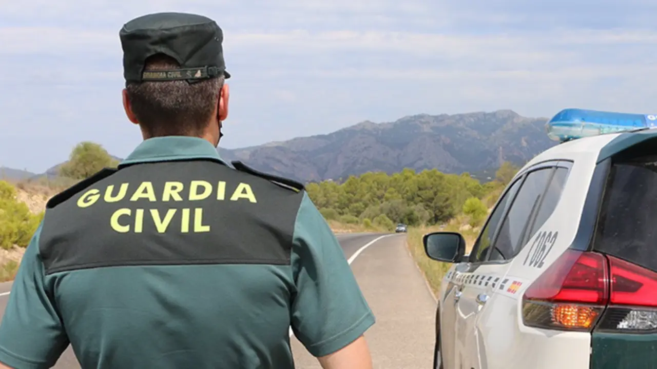  Archivo - Un agente de la Guardia Civil junto a un veh&iacute;culo en una carretera. (Foto de archivo). - GUARDIA CIVIL - Archivo 