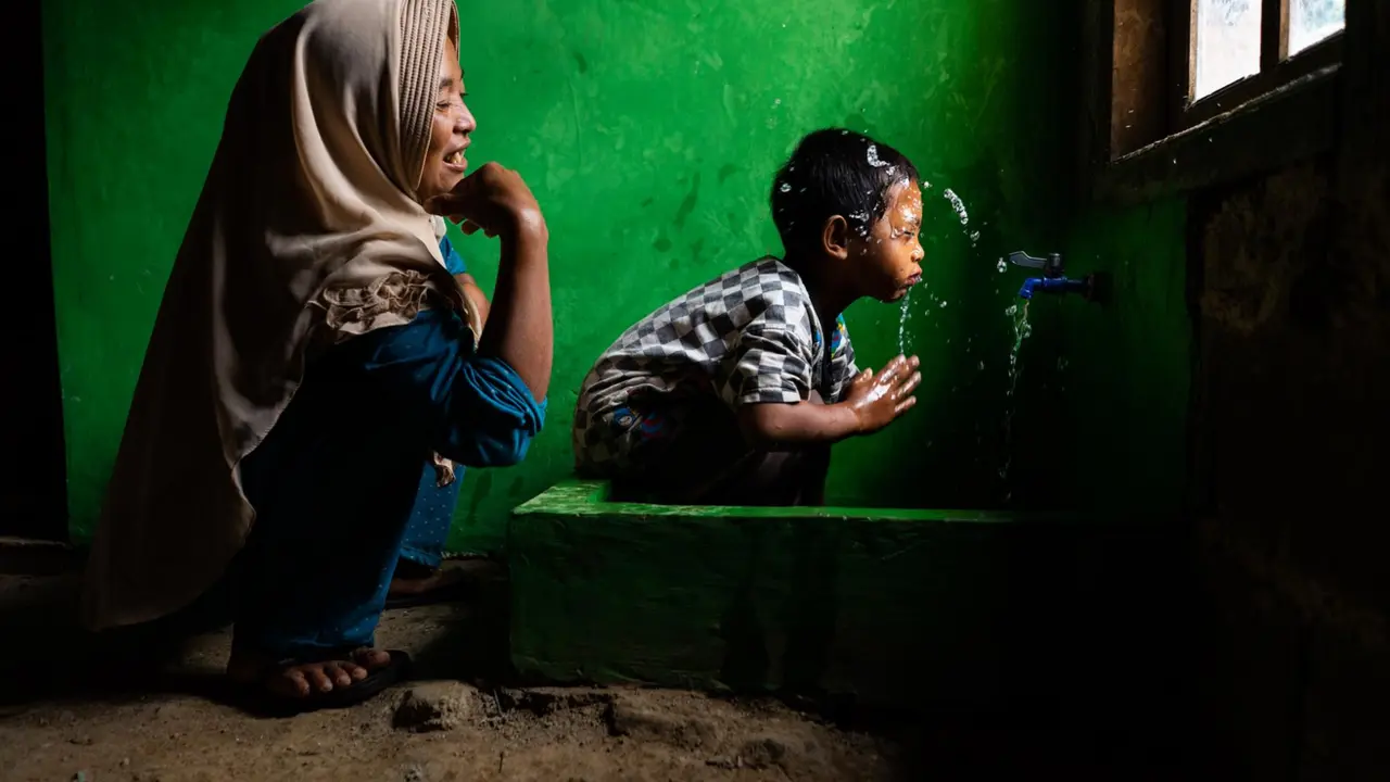  Archivo - Wahyu observa a su hijo Rizki, de 4 a&ntilde;os, lav&aacute;ndose la cara en una nueva instalaci&oacute;n de agua potable en su casa, en Tlogopakis, Indonesia. - UNICEF/IJAZAH - Archivo 