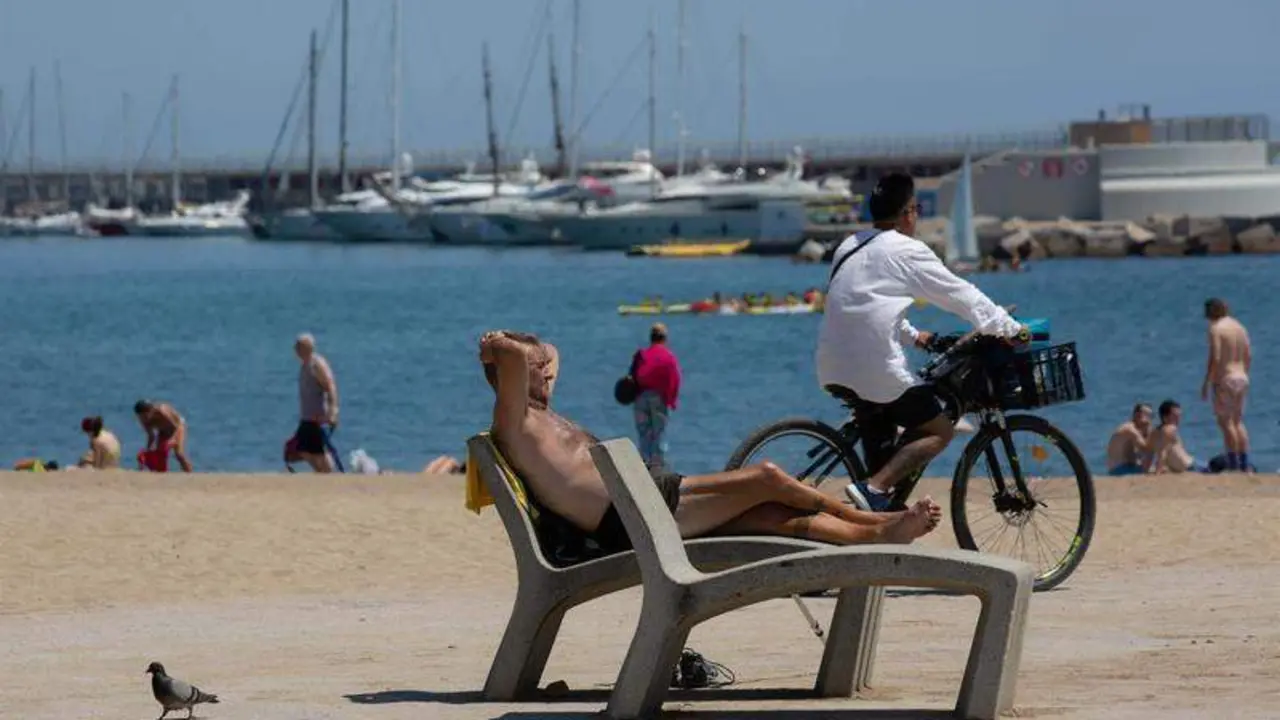  Varias personas toman el sol en la playa de la Barceloneta, a 13 de julio de 2022 