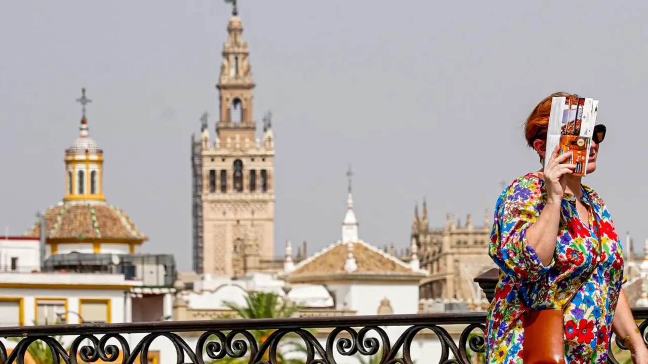  Una persona paseando por el Puente de Triana se protege la cara el d&iacute;a en que la capital est&aacute; en alerta naranja por el calor , a 19 de julio del 2023. - Eduardo Briones - Europa Press 