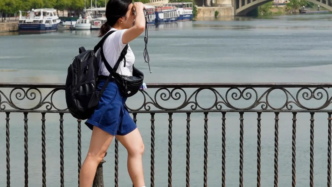  Una persona paseando por el Puente de Triana se protege la cara el d&iacute;a en que la capital est&aacute; en alerta naranja por el calor , a 19 de julio del 2023. - Eduardo Briones - Europa Press 