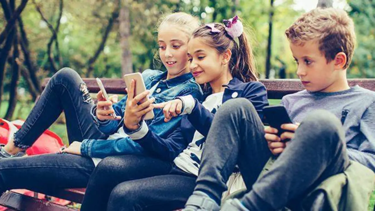  Ni&ntilde;os con tel&eacute;fonos en el parque 