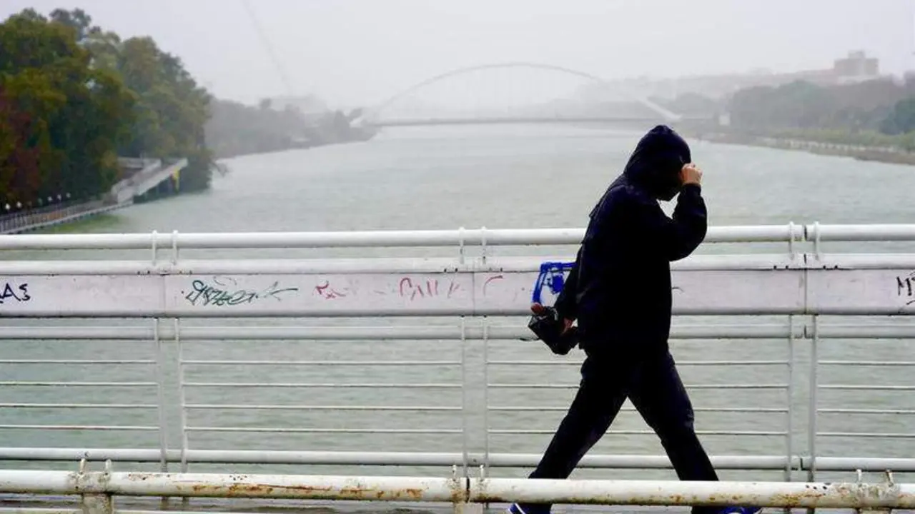  Imagen de archivo de un persona protegi&eacute;ndose de la lluvia y el viento en Sevilla 