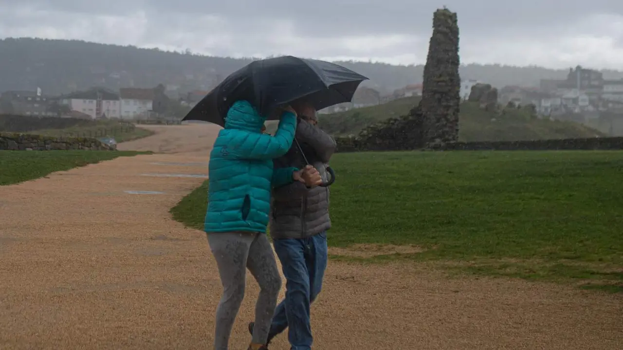  Dos personas se protegen de la lluvia con un paraguas 