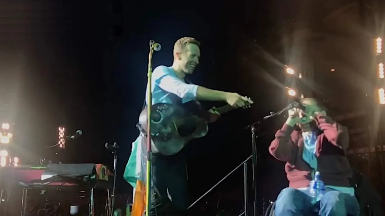  Chris Martin durante su concierto con uno de sus fans en el escenario | YouTube. 