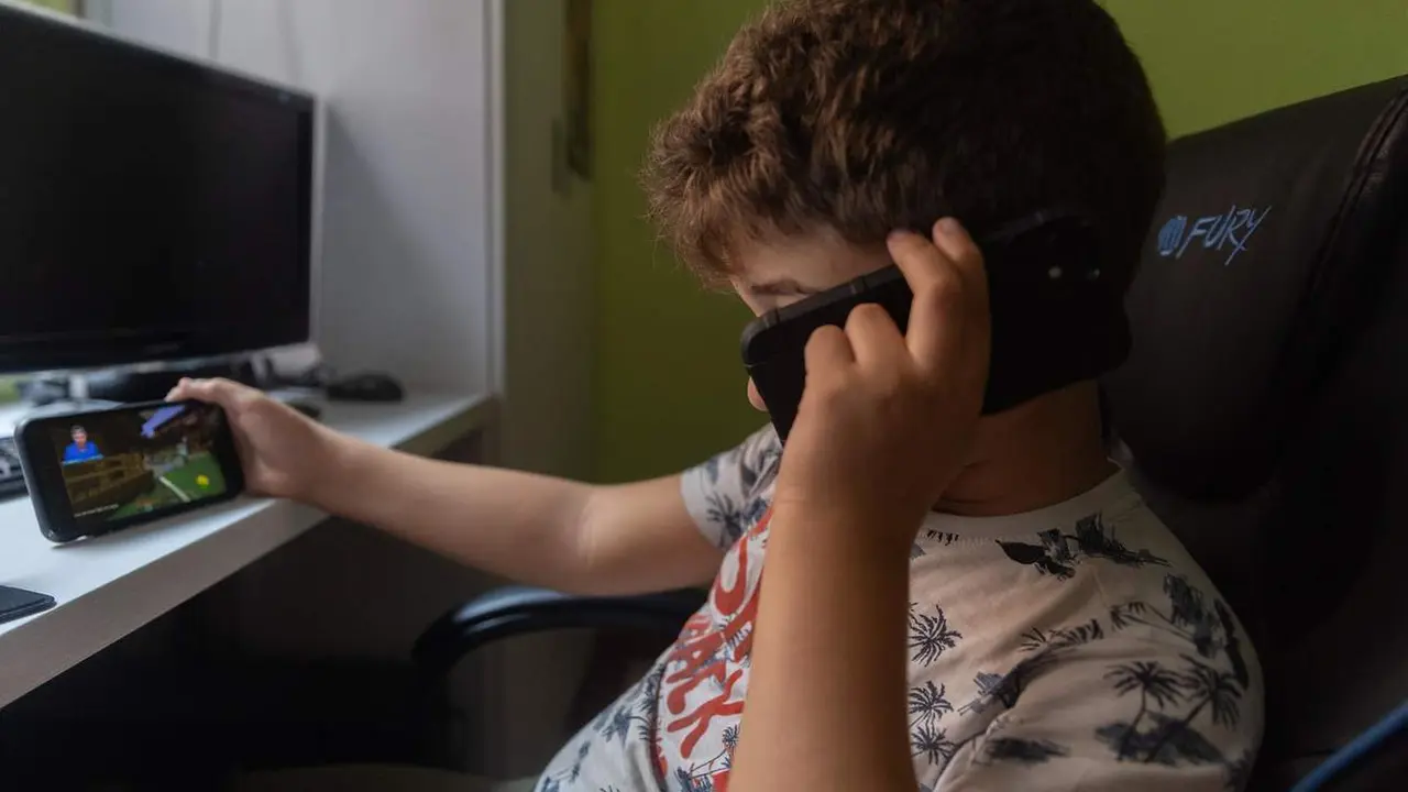  Un ni&ntilde;o usa el tel&eacute;fono para ver v&iacute;deos 