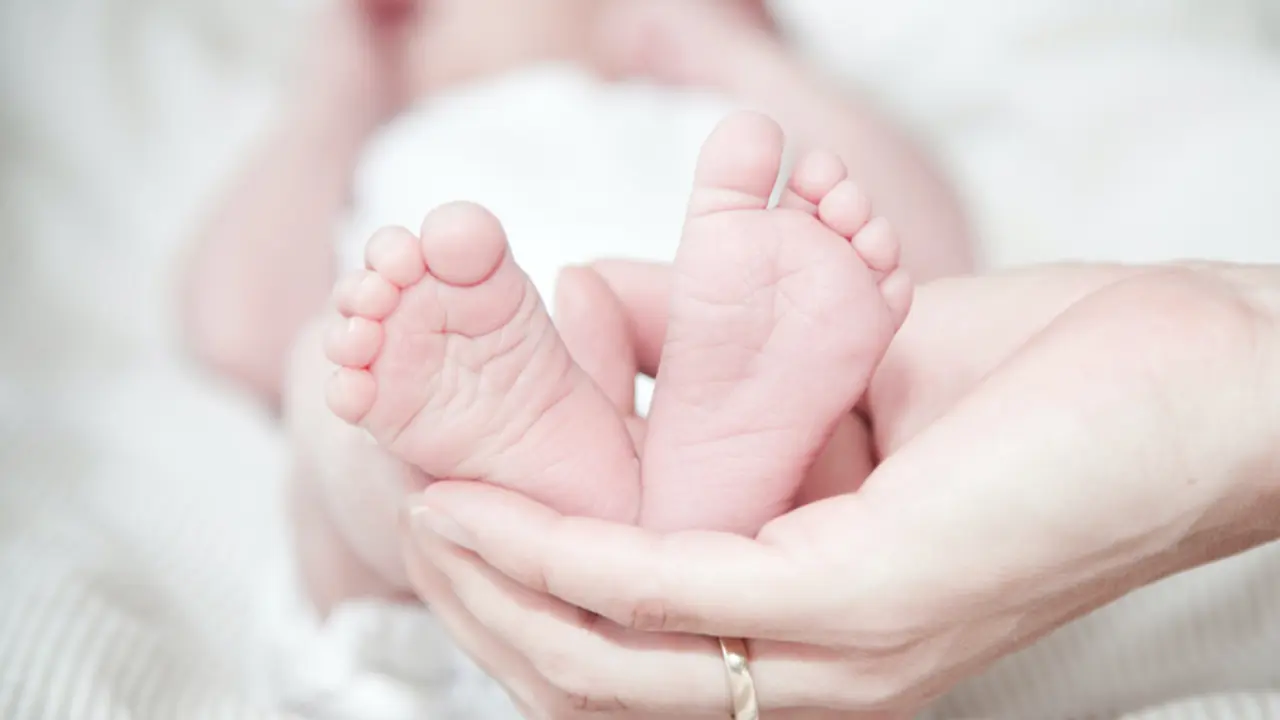  Las manos de una madre sostienen los pies de su beb&eacute;. 