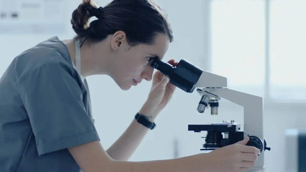  Investigadora mirando por un microscopio - MICIU 