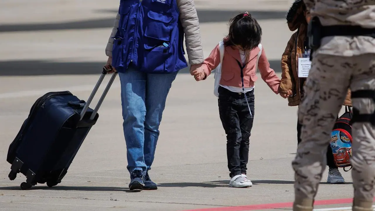  Una ni&ntilde;a procedente de Siria de la mano de una trabajadora de una organizaci&oacute;n a su llegada a la base a&eacute;rea de Torrej&oacute;n de Ardoz, a 19 de mayo de 2023 