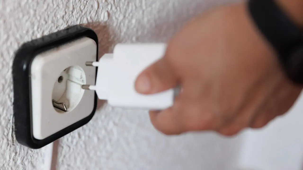  Archivo - Una persona sujeta un cargador frente a un enchufe - Eduardo Parra - Europa Press - Archivo 