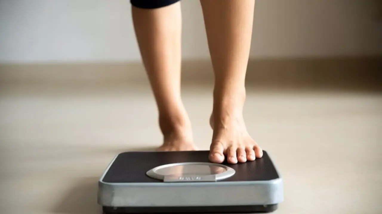  Female leg stepping on weigh scales. Healthy lifestyle, food and sport concept. 