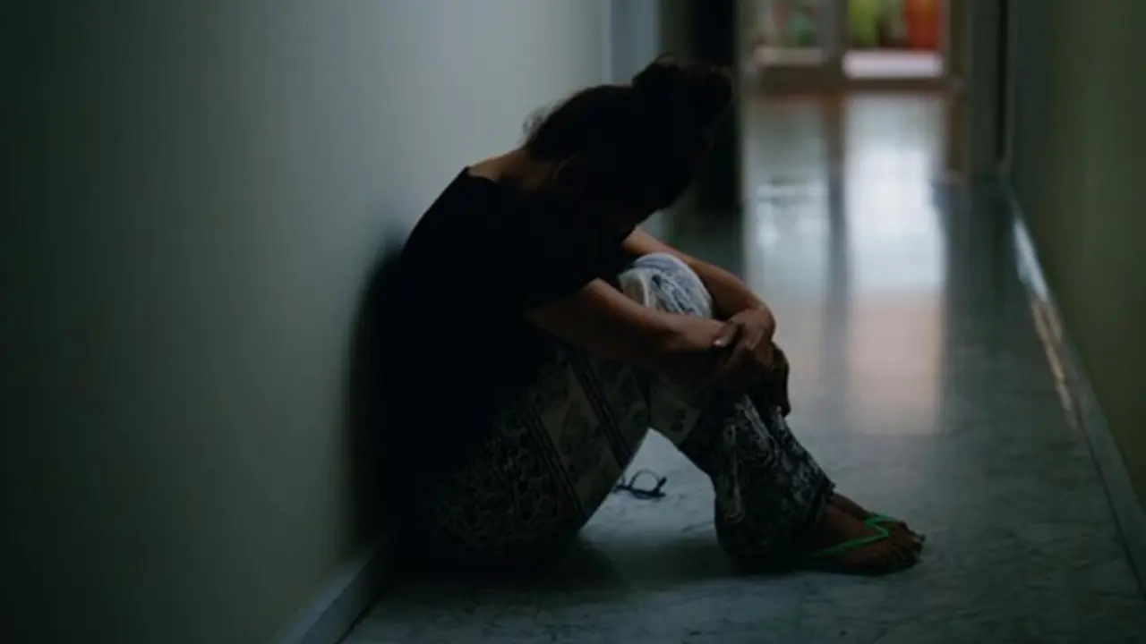  Una joven expresa su malestar sentada en un pasillo. 