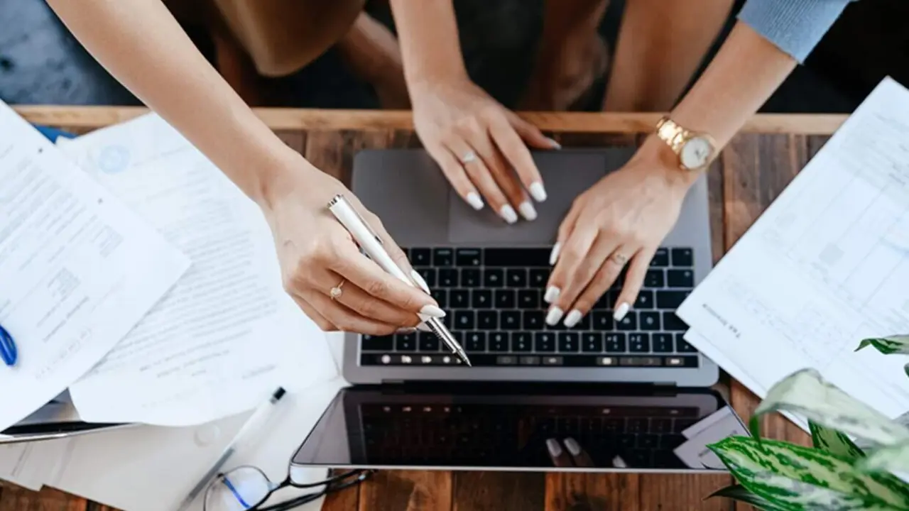  Trabajadores consultan un dispositivo port&aacute;til. 