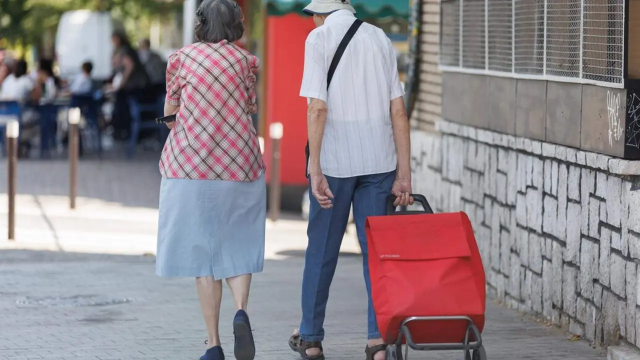  Una pareja de mayores caminan con un carro de la compra 