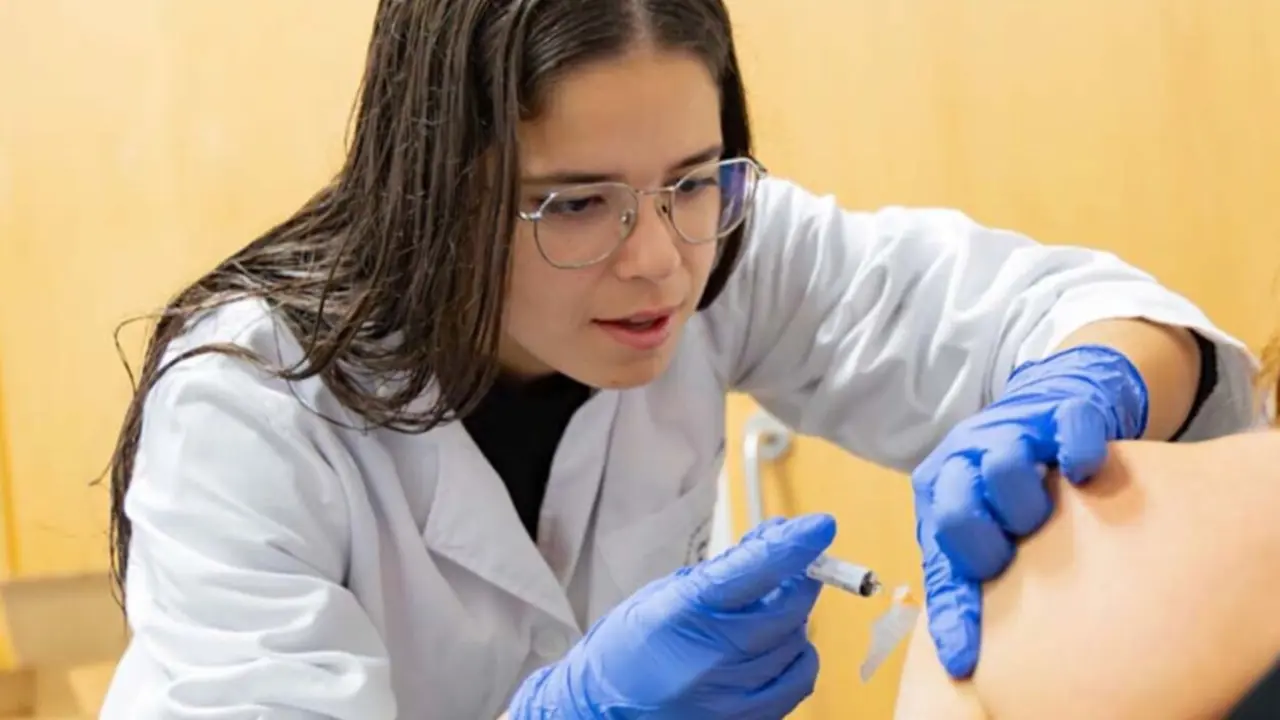  Una enfermera administra la vacuna de la gripe a una paciente. 