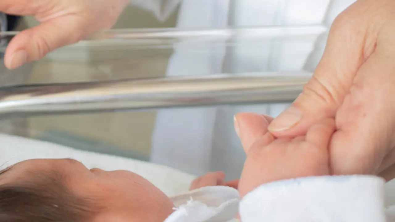  Una enfermera toma la mano a un reci&eacute;n nacido. 