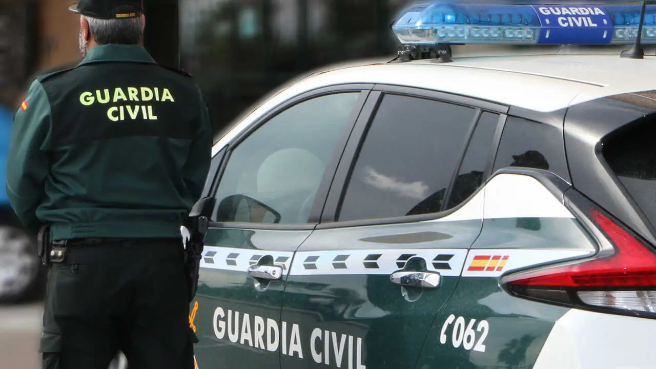 Archivo - Un agente de la Guardia Civil, de espaldas, de pie junto a un veh&iacute;culo oficial.