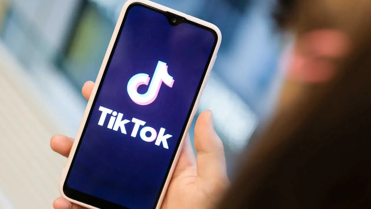 Archivo - FILED - 13 November 2019, Berlin: A girl holds a smartphone that displays a picture of short video app TikTok. the Beijing-based social media platform has apologized for removing a viral video criticizing the mass internment of Muslims in China.