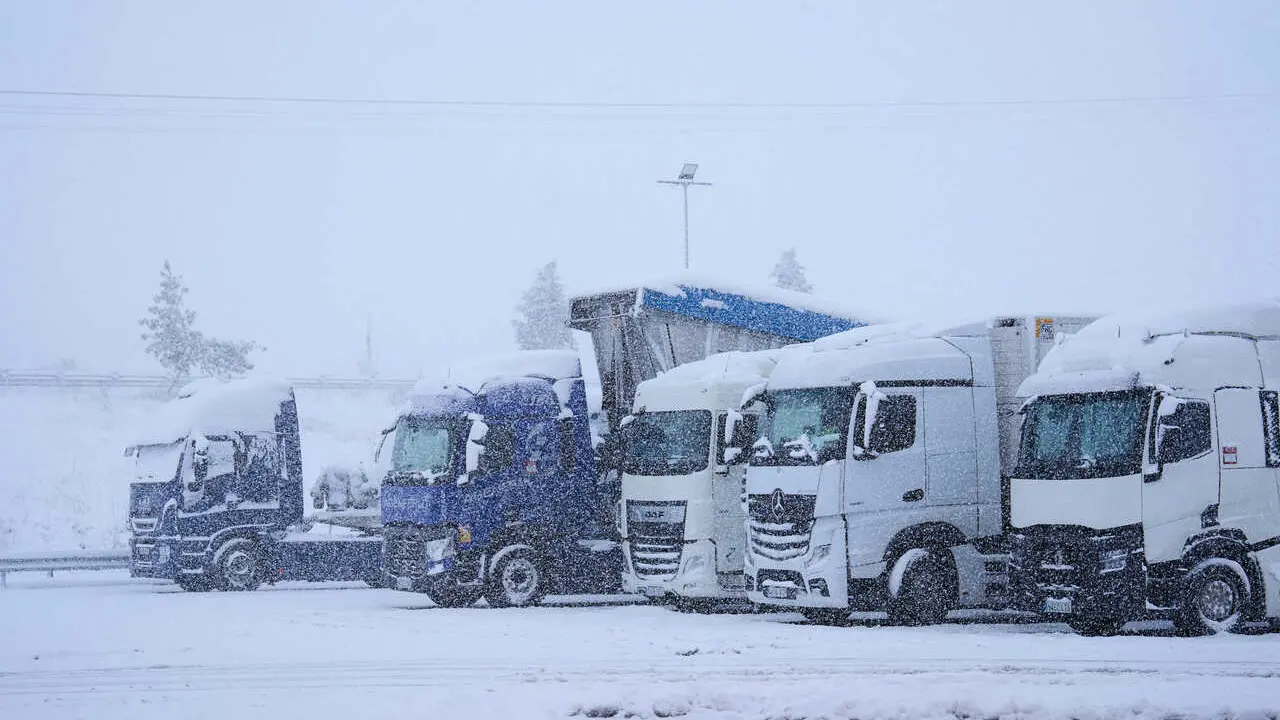 Archivo - Varios camiones parados por la nieve