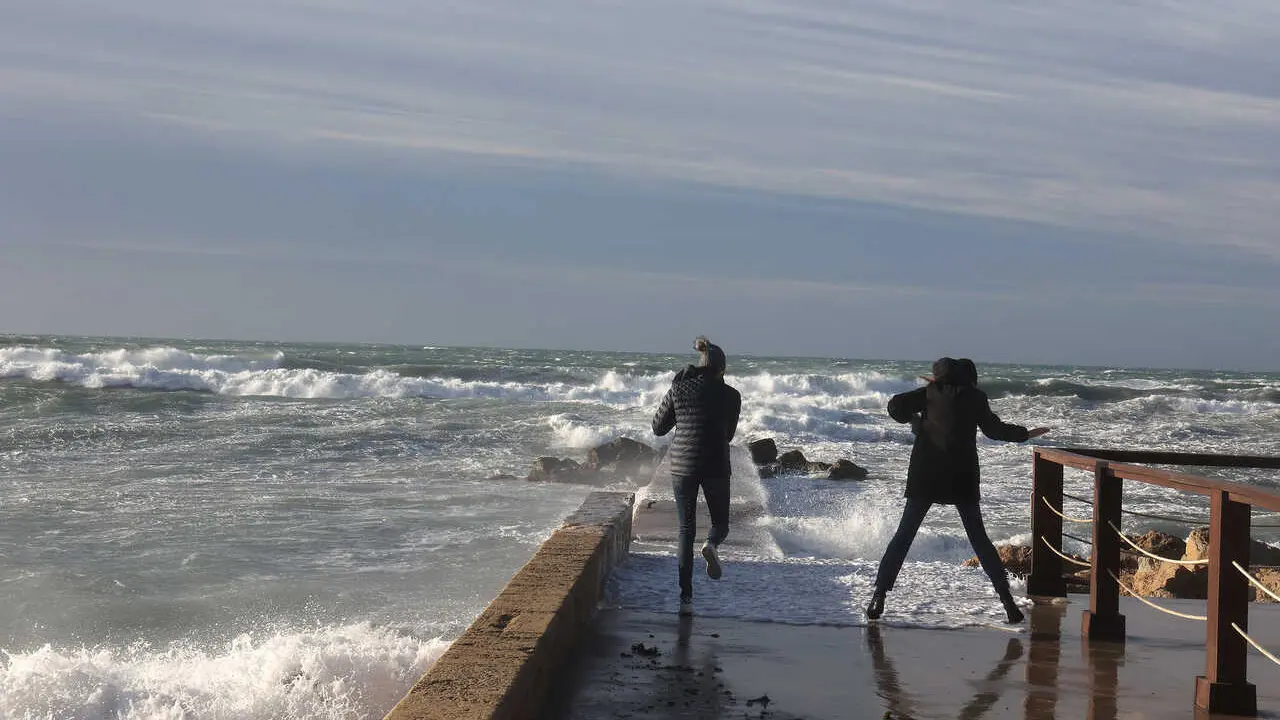 Archivo - Dos personas fotograf&iacute;an el oleaje causado por el viento