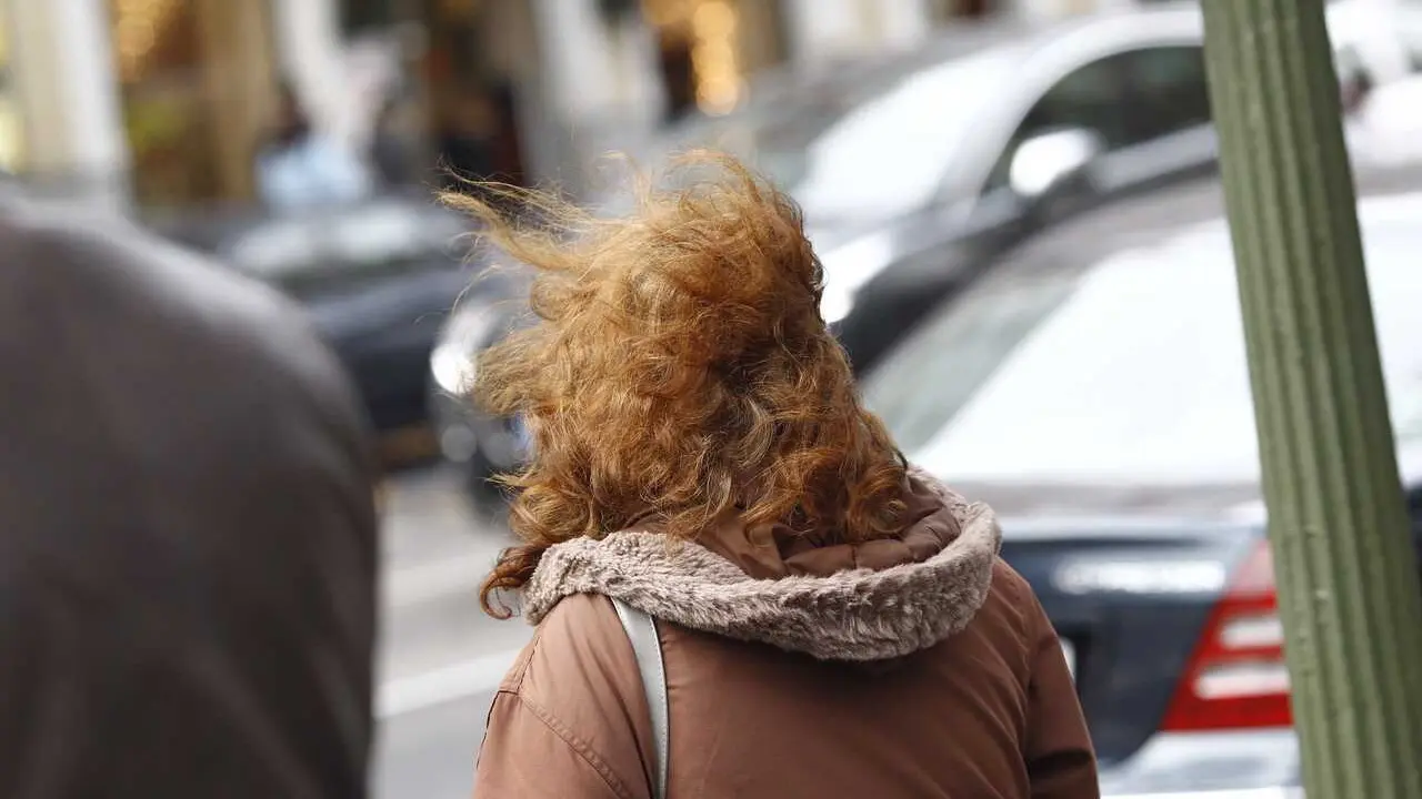 Archivo - Una mujer camina por la calle en un d&iacute;a de viento. Imagen de archivo