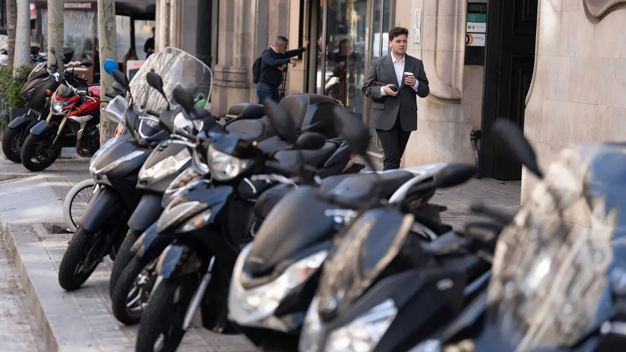 Archivo - Varias personas caminan al lado de motos 