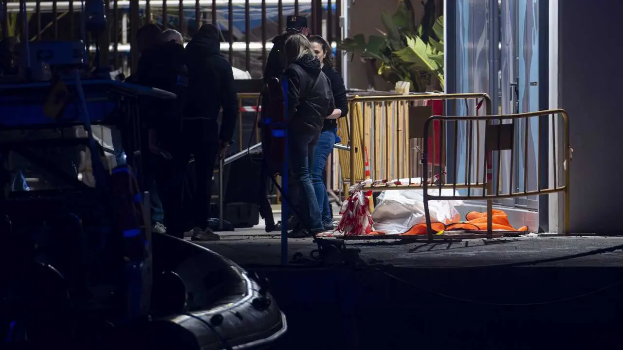 Varias personas junto al cad&aacute;ver aparecido en la playa del Somorrostro de Barcelona