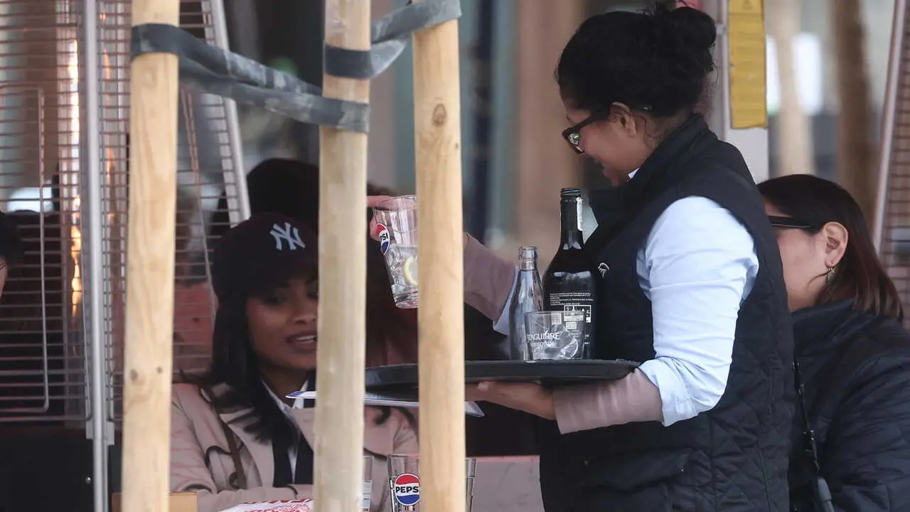 Archivo - Una camarera extranjera atendiendo a unos clientes