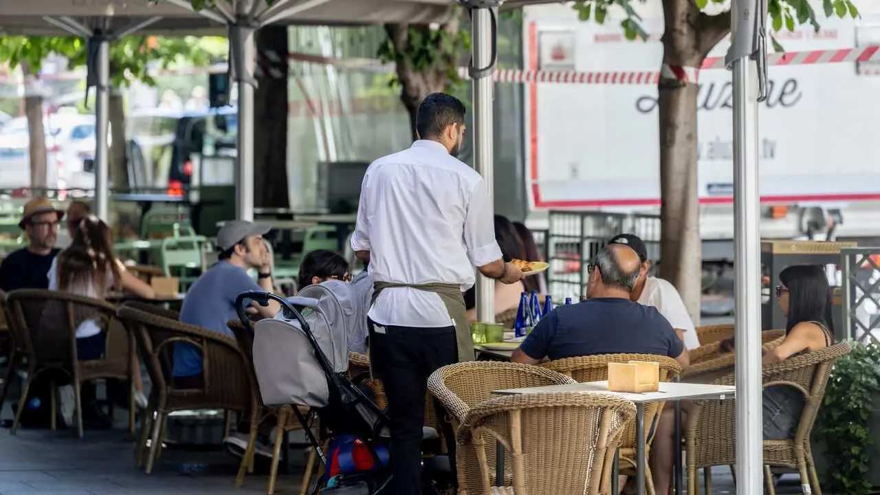Archivo - Un camarero atendiendo la terraza de un bar en la temporada de verano