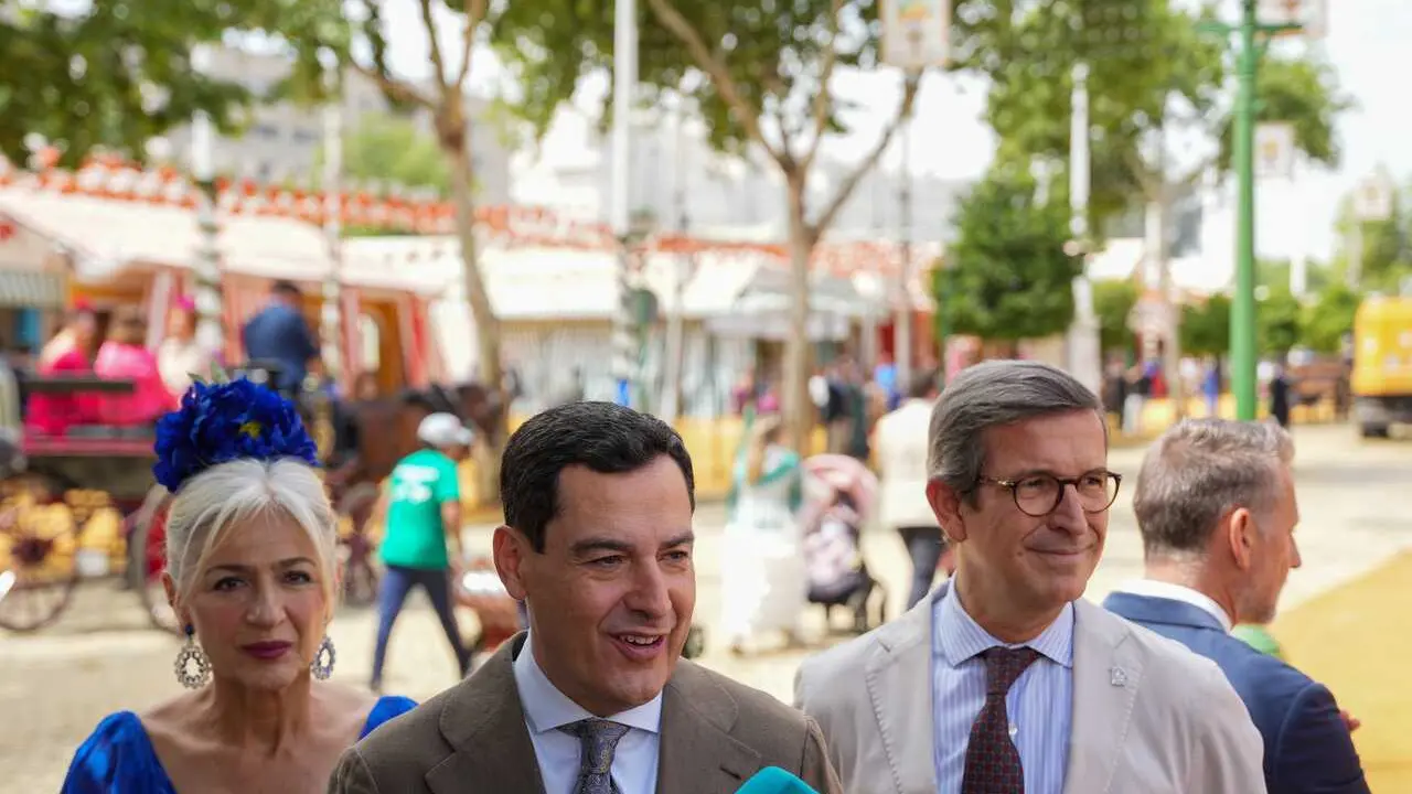 El presidente de la Junta de Andaluc&iacute;a, Juanma Moreno (c), junto a la consejera de Cultura, Patricia del Pozo, y el consejero de Industria, Jorge Paradela (d), atienden a los medios a su llegada a la Feria de Abril. A 22 de abril de 2026, en Sevilla