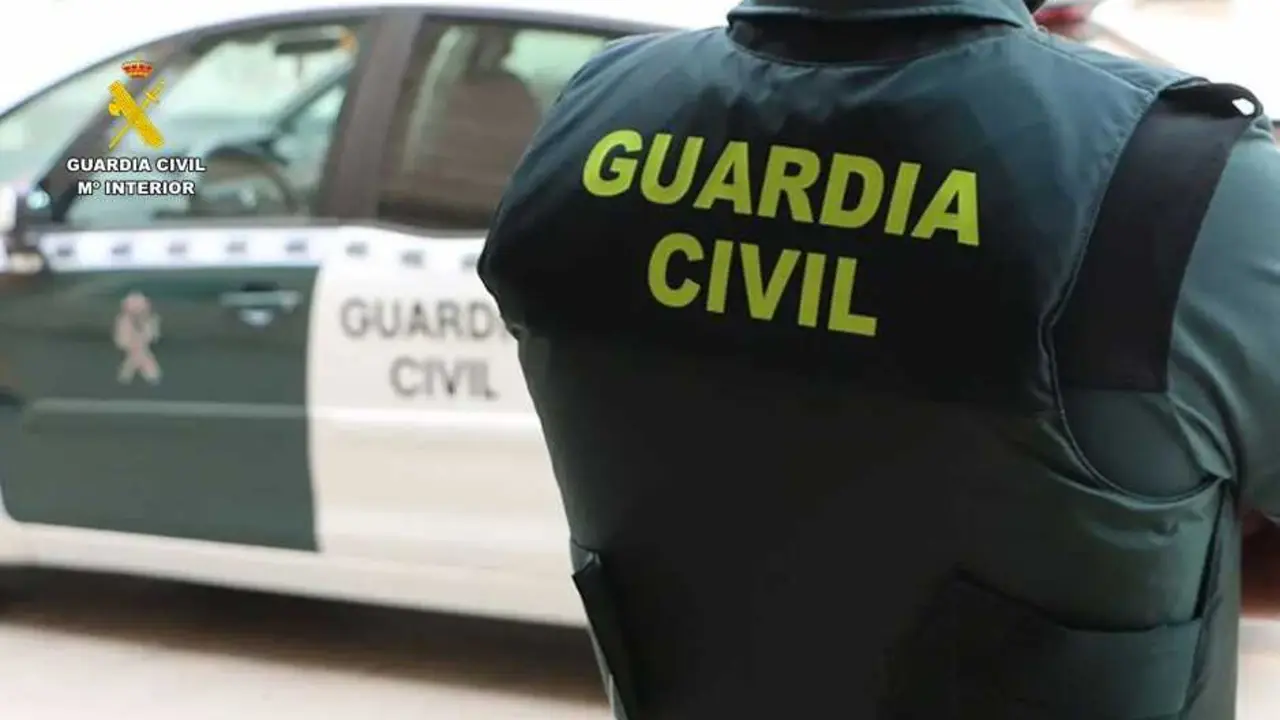 Archivo - Un agente de la Guardia Civil junto a un veh&iacute;culo oficial.