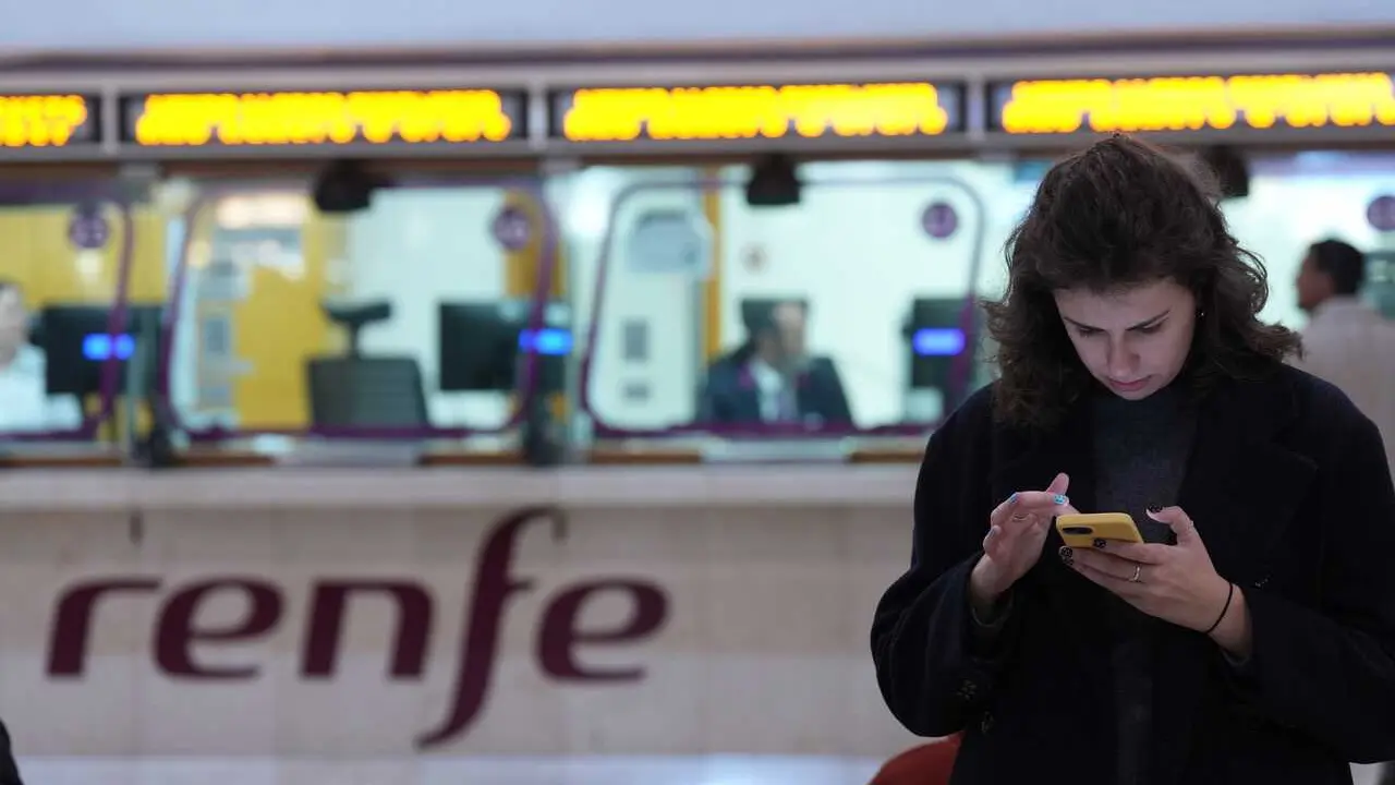 Archivo - Una persona espera en la Estaci&oacute;n de Sants ante una ventanilla de Renfe