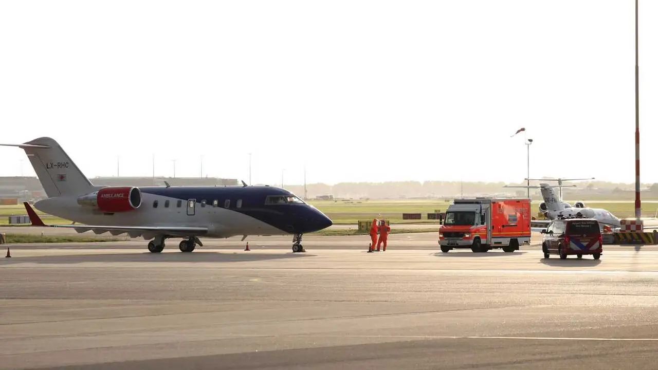 06 May 2026, Netherlands, Amsterdam: Medical staff in protective suits wait next to a German ambulance to receive the patients who have been evacuated from the hantavirus-hit cruise ship MV Hondius, after their arrival at Schiphol Airport in Amsterdam. Ph