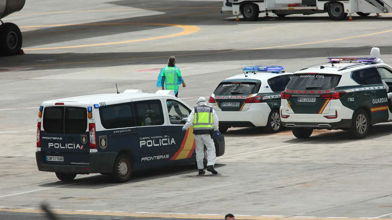 Polic&iacute;as nacionales, guardias civiles y militares de la UME vestidos con monos EPI y mascarillas coordinan a los viajeros evacuados del crucero MV Hondius, en el aeropuerto de Tenerife Sur, a 10 de mayo de 2026, en Tenerife, Islas Canarias (Espa&ntilde;a). El op