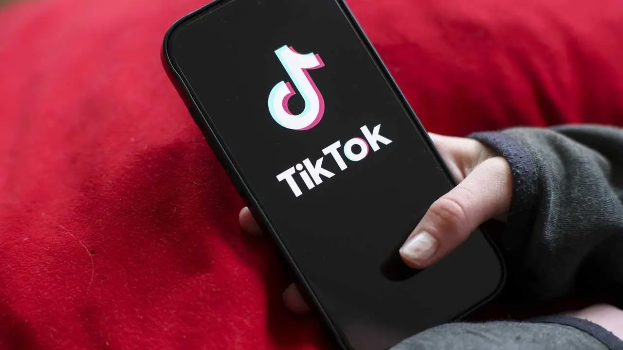 Archivo - A girl holds an iPhone 16 with the logo of the TikTok app on it. 