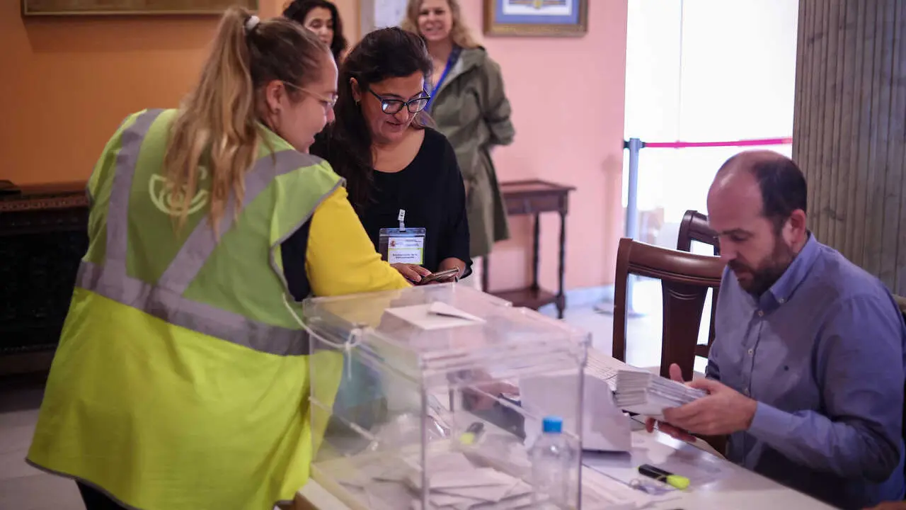 Archivo - Una integrante de Correos llega a la mesa electoral para entregar los votos ejercido por este m&eacute;todo en Sevilla, en una imagen de archivo