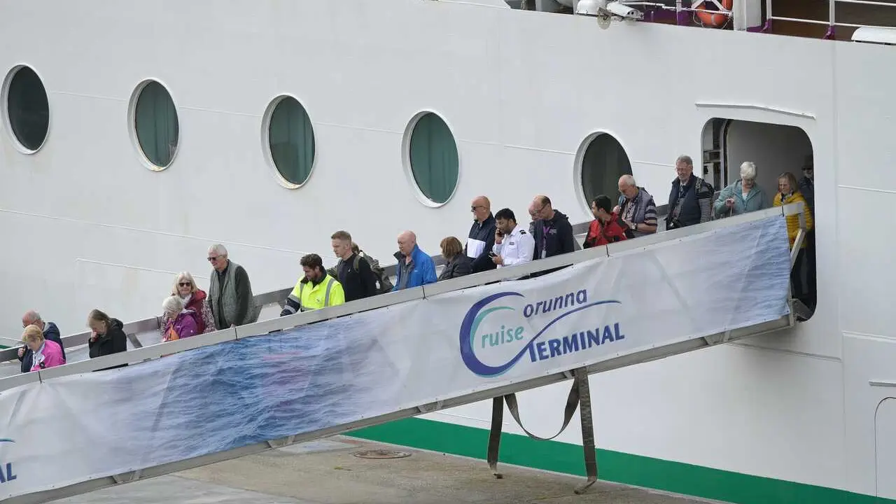 Personal sanitario (con chalecos amarillos) desembarca con pasajeros del crucero 'Ambition', aislado por un brote de gastroenteritis, durante una escala en el puerto de A Coru&ntilde;a