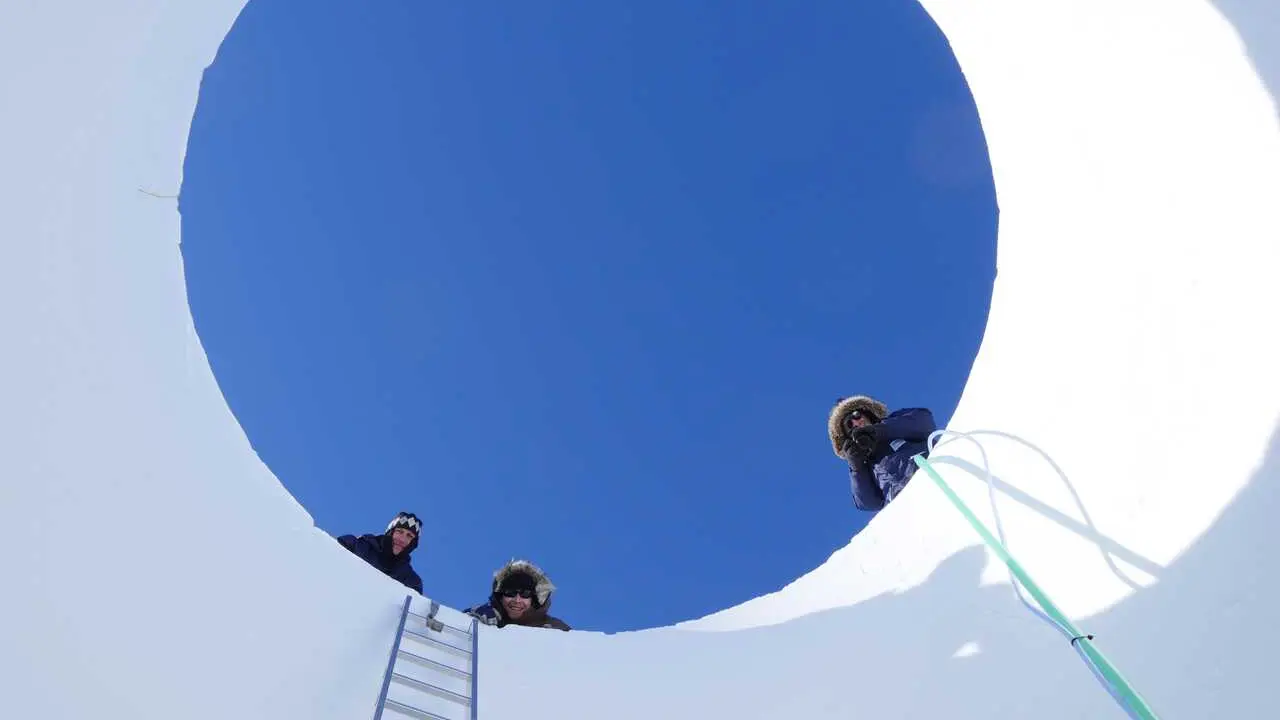 Investigadores asomados al n&uacute;cleo de hielo analizado.
