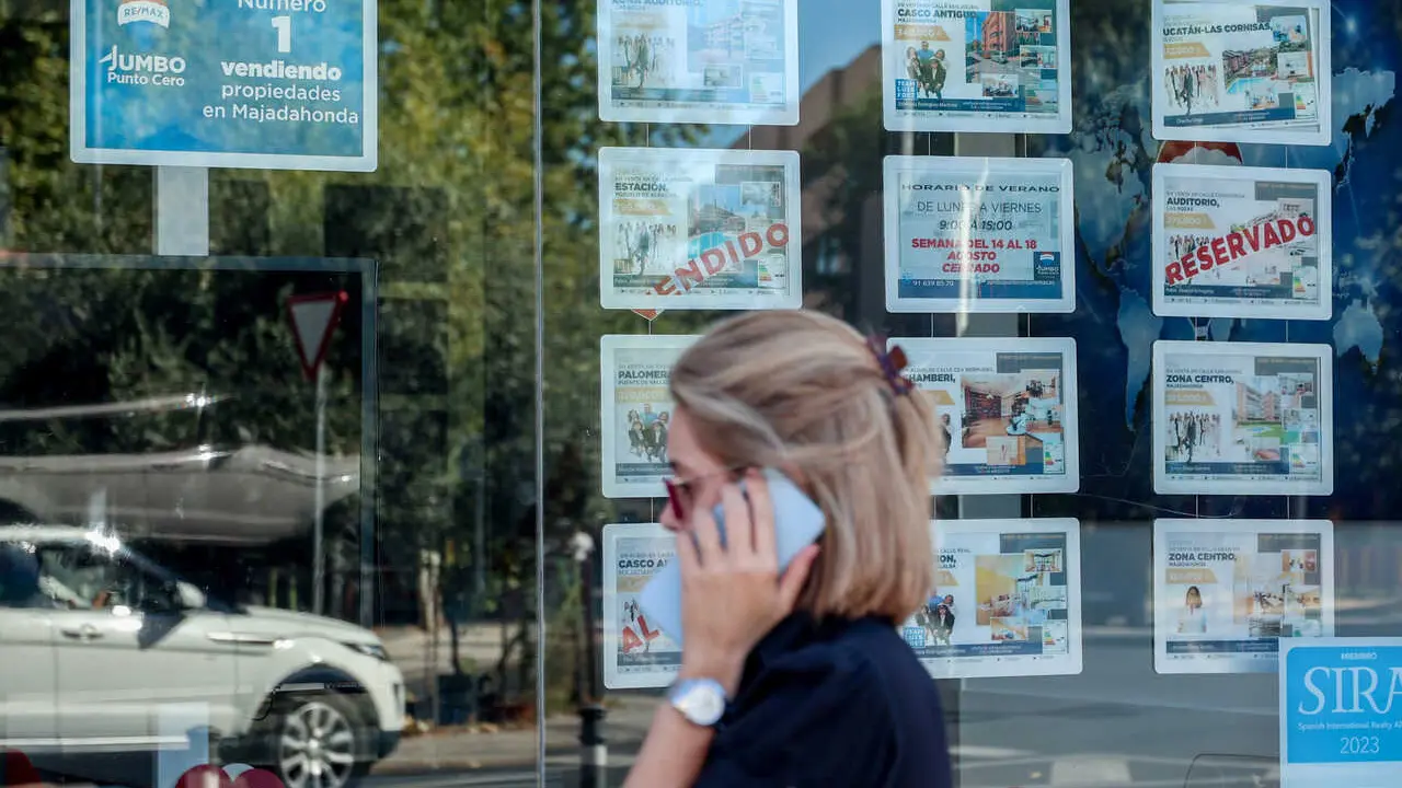 Archivo - Una mujer pasa frente a un escaparate de anuncios de viviendas en Madrid (Espa&ntilde;a)